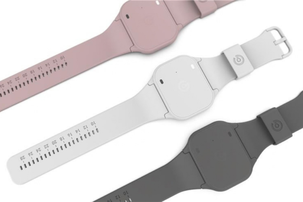 Three adjustable Glucowear™ devices in light pink, white, and dark grey on a white background, each with a rectangular buckle and measurement markings along the strap.